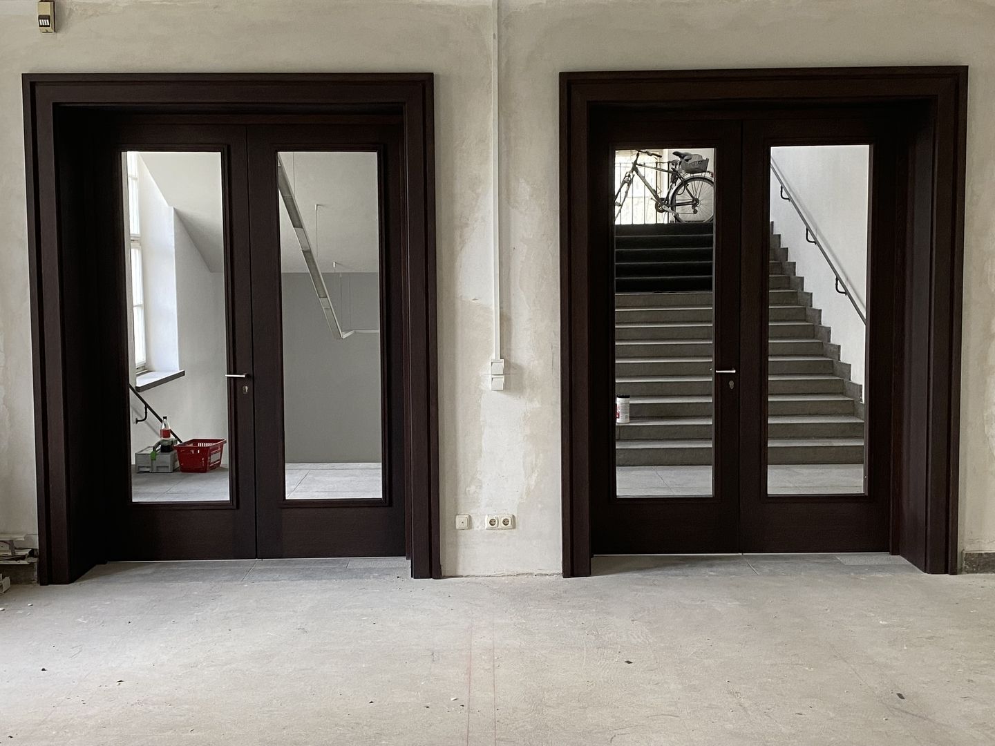 Zwei Türen in einem leeren Raum mit einer Treppe, die in die Höhe führt.